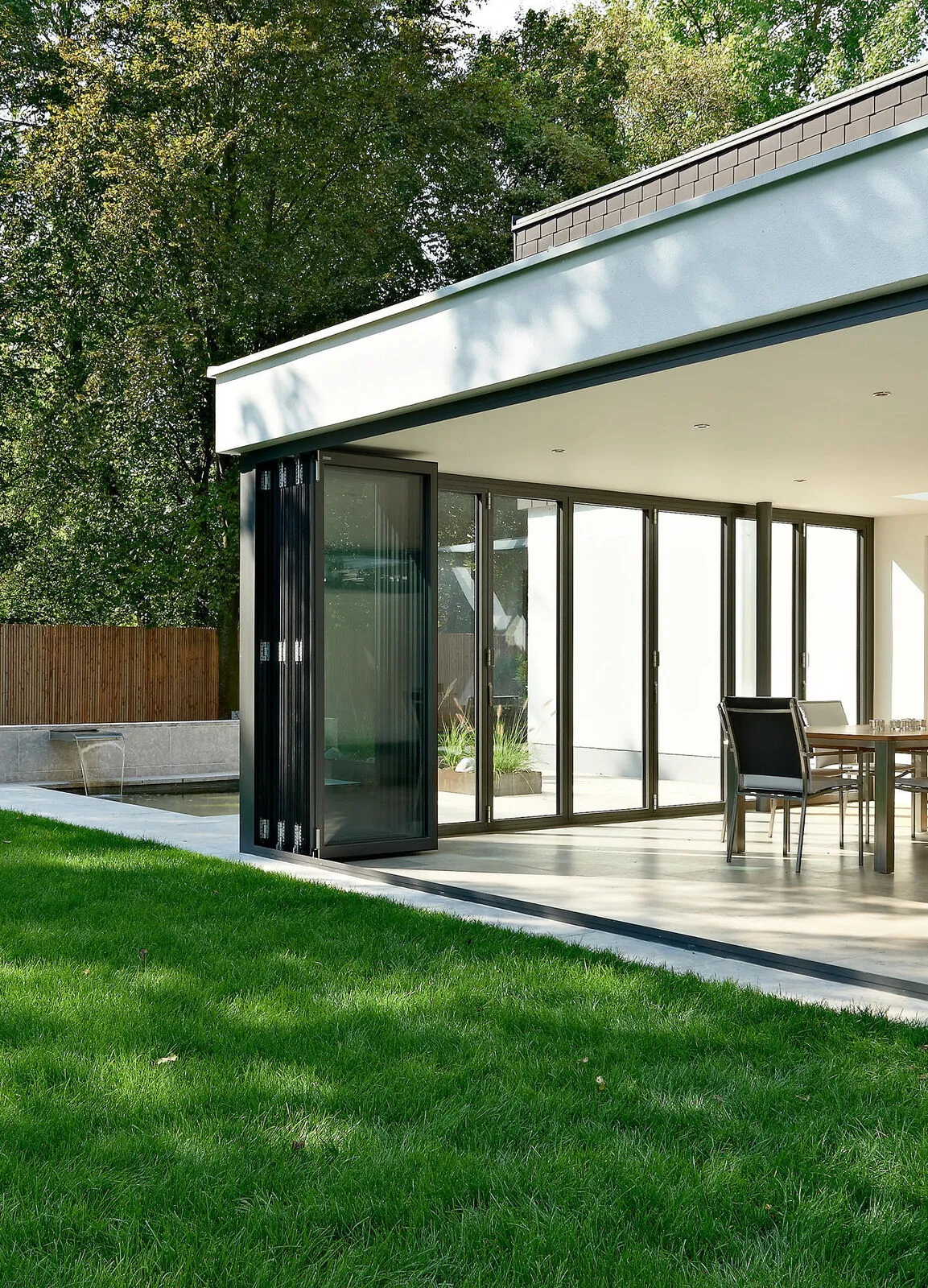 Slim folding doors wrapping a garden corner of a brick extension